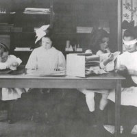 Girls doing the touch exercises with pieces of fabric. The girl on the right is blindfolded so as to concentrate all her attention on the sense of touch. The photograph, from 1912, belonged to S. S. McClure of New York, the publisher of the famous McClure's Magazine, which in 1911/12 published a number of articles and photographs and had a decisive influence on the birth of the American Montessori movement. This photograph (like the other photographs by McClure in this book) was probably taken in the first American Children's House in Tarrytown N.Y., which was set up in 1911 and whose charges were all "from cultured families." (Kramer, p. 163) - T. Müller, R. Schneider, <em>Lehrmaterialien 1913-1935. Möbel und Architektur. Techning Meterials 1913-1935. Furniture and Architecture</em>, München, Prestel Verlag, 2002, p.93$$$455